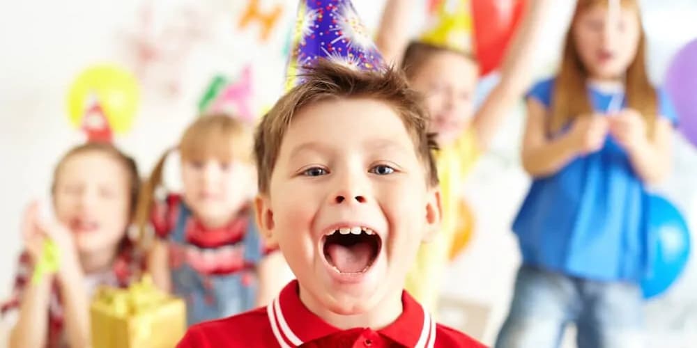 Kind lacht im Vordergrund, weitere Kinder feiern im Hintergrund.