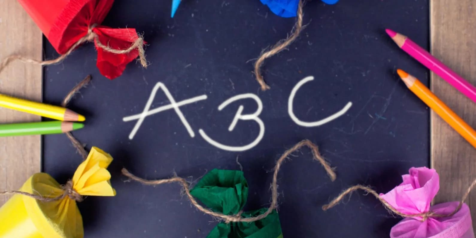 Die Buchstaben ABC auf einer Tafel mit Stiften und bunten Geschenkverpackungen